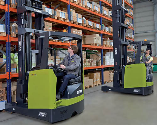 A picture of a warehouse and two people operating heavy machinery.