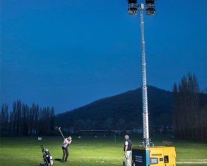 Atlas Copco lighting tower lighting a golf course while player takes a shot